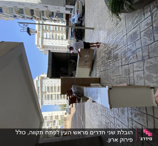 אדם מעמיס רהיטים למשאית הובלה ברחוב עירוני